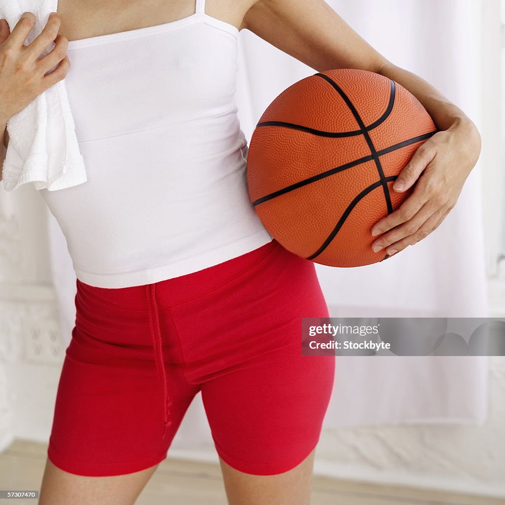 Young woman standing holding a basketball