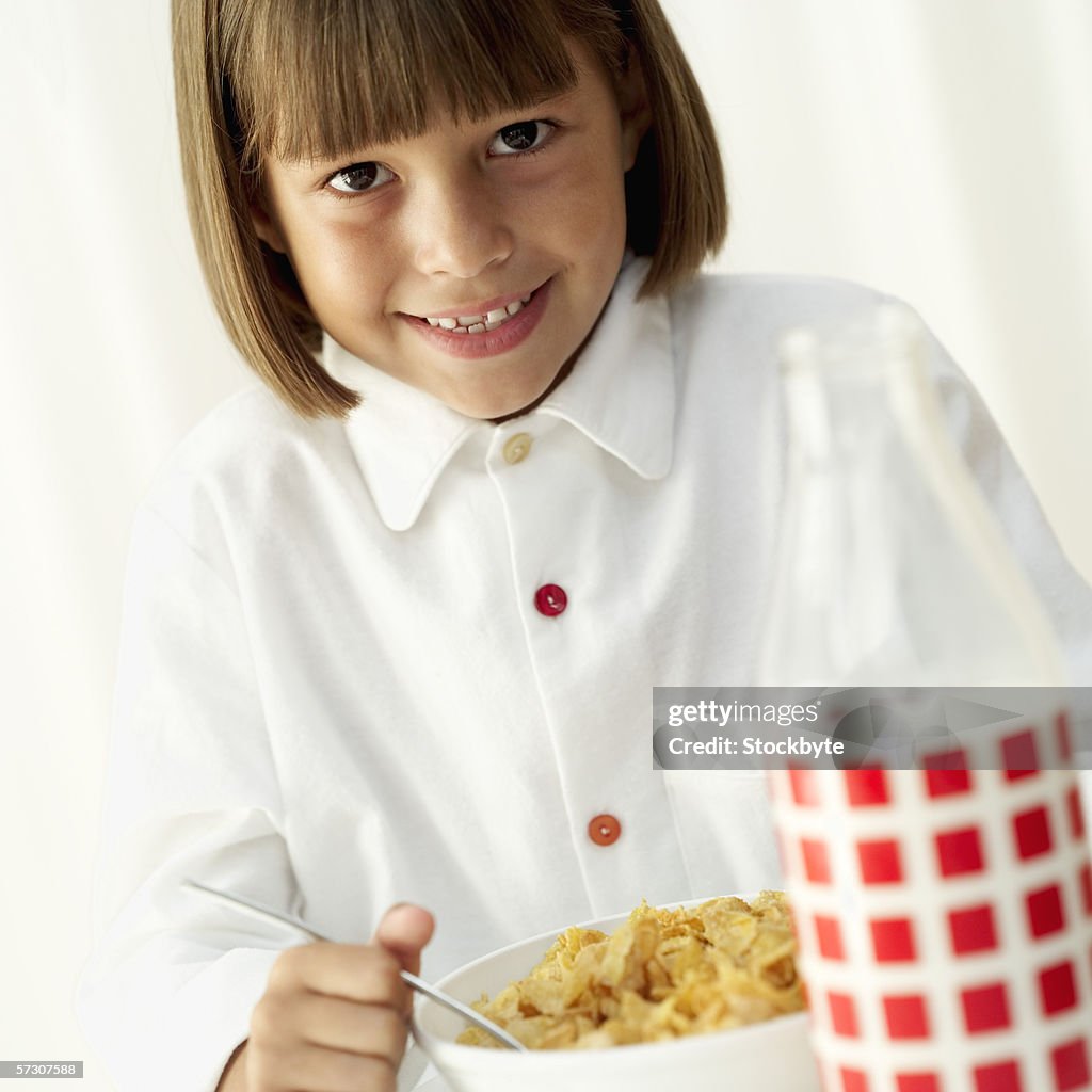Young girl (8-9) holding a spoon in a bowl of breakfast cereal