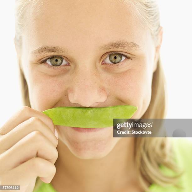 close-up of a girl holding a flat bean to her lips - ärtskida bildbanksfoton och bilder