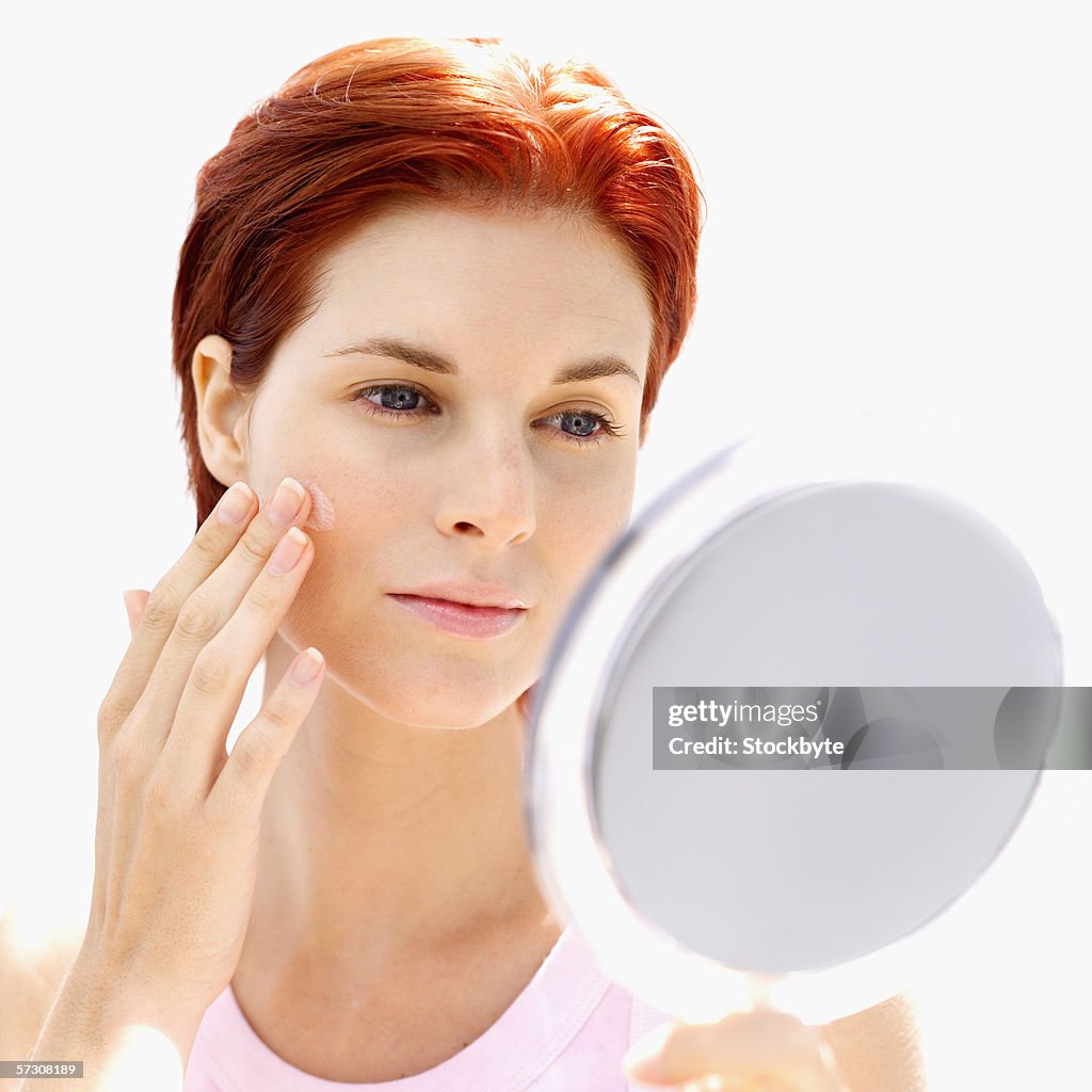 Young woman looking at her face in a mirror