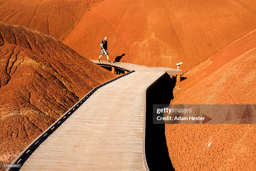 Caucasian hiker on wooden walkway in desert hills