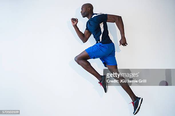 side view of black man running - black shorts stockfoto's en -beelden