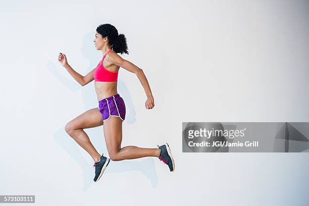side view of mixed race woman running - running shorts stock pictures, royalty-free photos & images