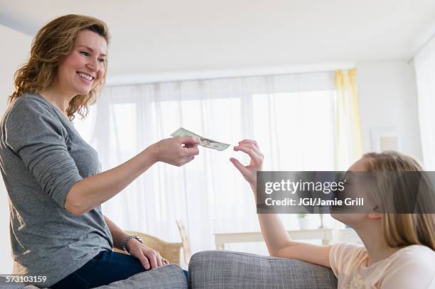 caucasian mother giving daughter money - pocket money stock pictures, royalty-free photos & images