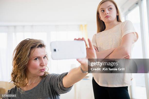 caucasian girl embarrassed of mother taking selfies with cell phone - peinlich stock-fotos und bilder