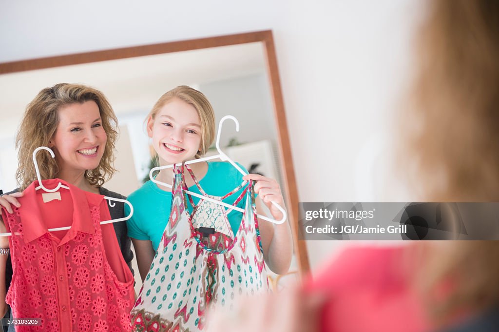 Caucasian mother and daughter examining shirts in mirror