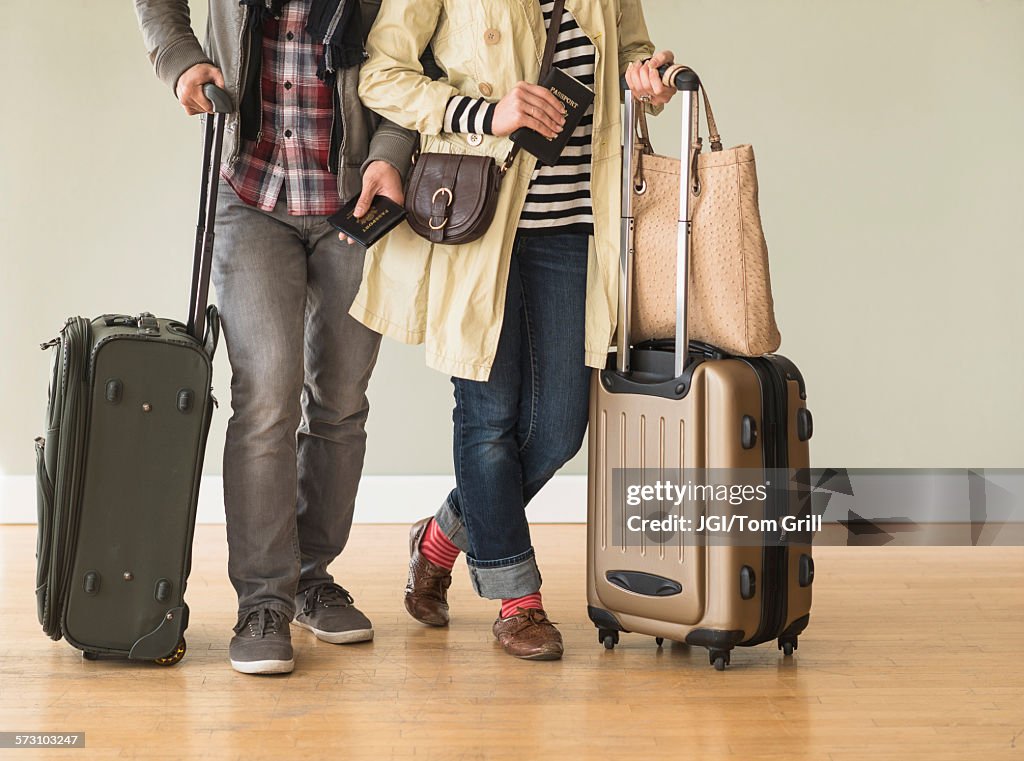 Couple holding rolling luggage in living room