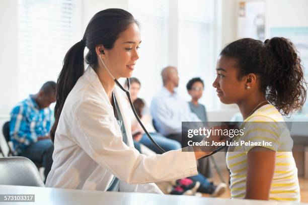 doctor listening to heartbeat of patient in volunteer clinic - womans clinic heart stockfoto's en -beelden