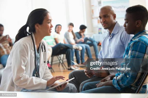 doctor using digital tablet with patients in volunteer clinic - teen and doctor fotografías e imágenes de stock