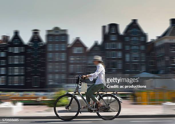 blurred view of bicyclist on amsterdam street, netherland - amsterdam bike stock-fotos und bilder