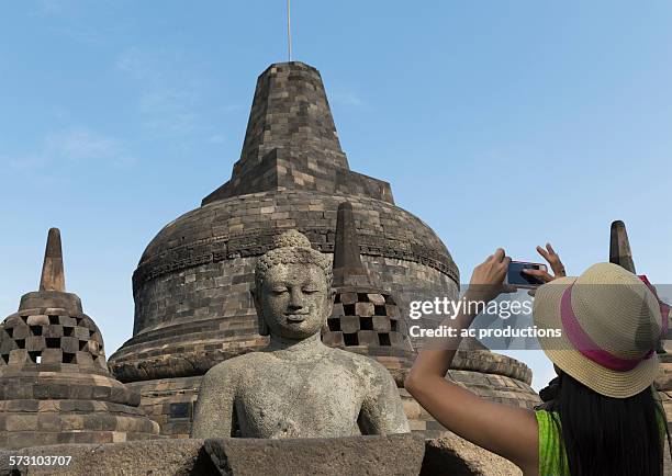 tourist photographing buddha statue on temple of borobudur, borobudur, indonesia - borobudur temple stock pictures, royalty-free photos & images