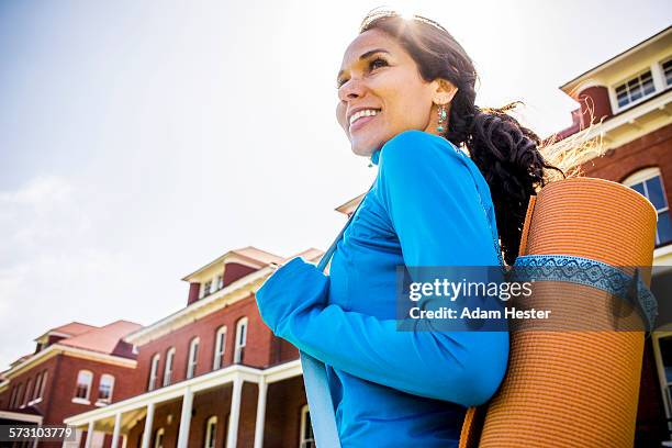 hispanic woman carrying yoga mat outdoors - 35 female outdoors stock-fotos und bilder