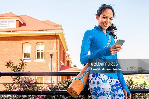 hispanic woman with yoga mat using cell phone - mobile phone reading low angle stock pictures, royalty-free photos & images