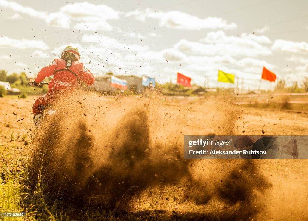 Caucasian motocross biker spraying dirt on race course