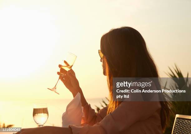 hispanic woman drinking champagne at sunset dinner outdoors - solo una donna giovane foto e immagini stock