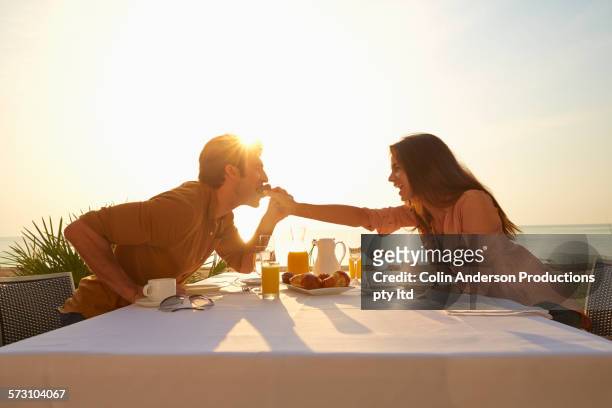 hispanic woman feeding man at sunset dinner outdoors - couple dinner imagens e fotografias de stock