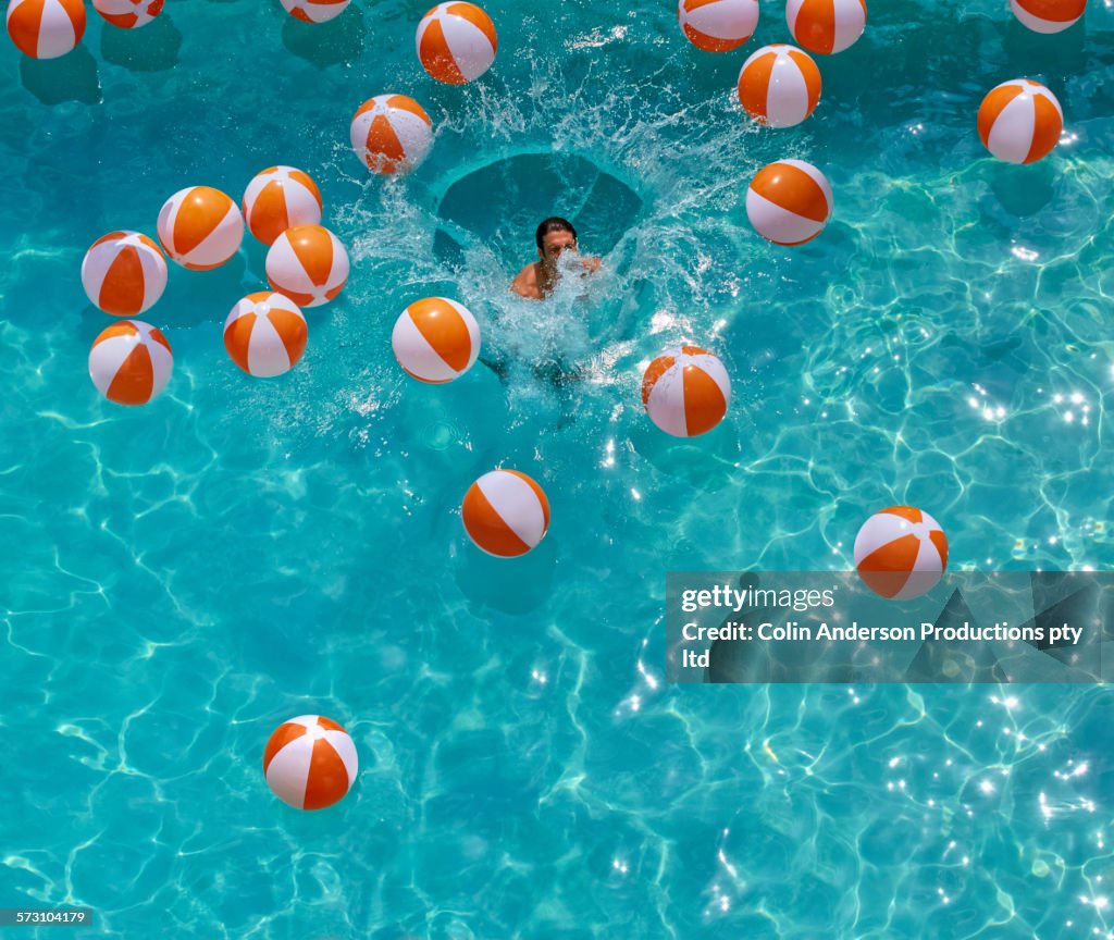 Overhead view of Hispanic man jumping in swimming pool