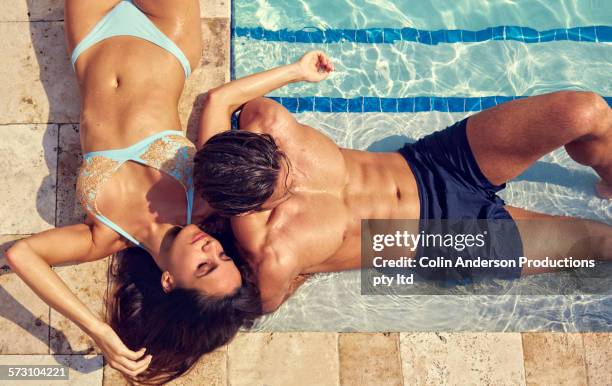 hispanic couple relaxing at swimming pool - women sunbathing pool - fotografias e filmes do acervo