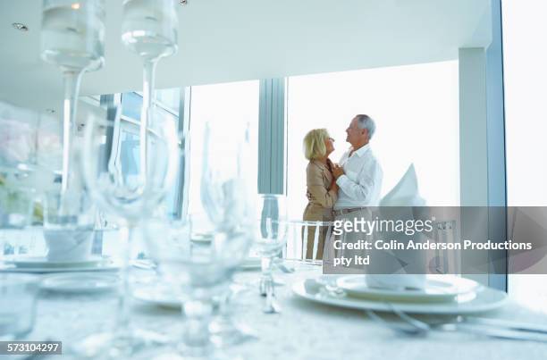 older caucasian couple holding hands in dining room - senior man dancing on table stock pictures, royalty-free photos & images