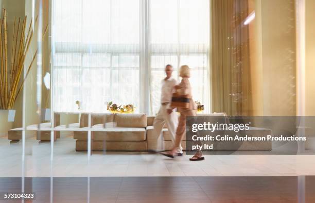 older caucasian couple walking in hotel lobby - lobby foto e immagini stock