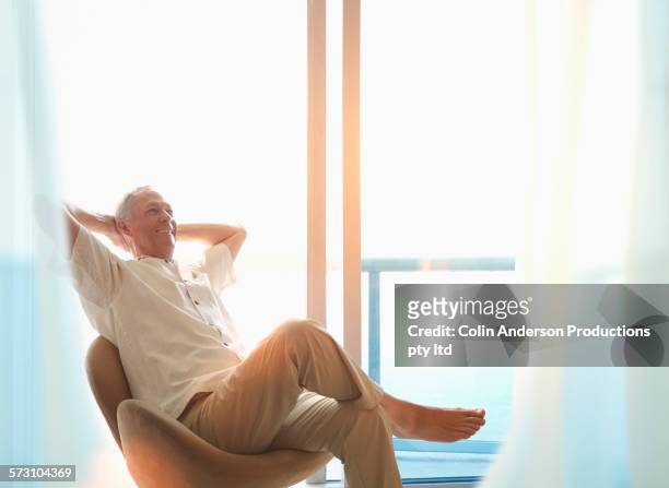 older caucasian man sitting at window - rico e anderson fotografías e imágenes de stock