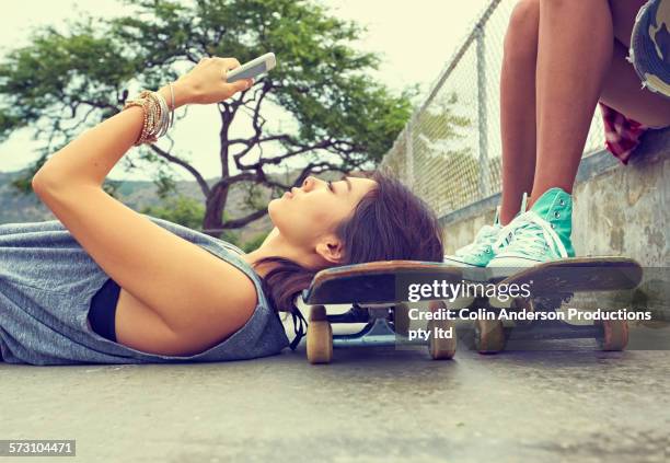 woman using cell phone on skateboard at skate park - ボード　持つ　女性 ストックフォトと画像