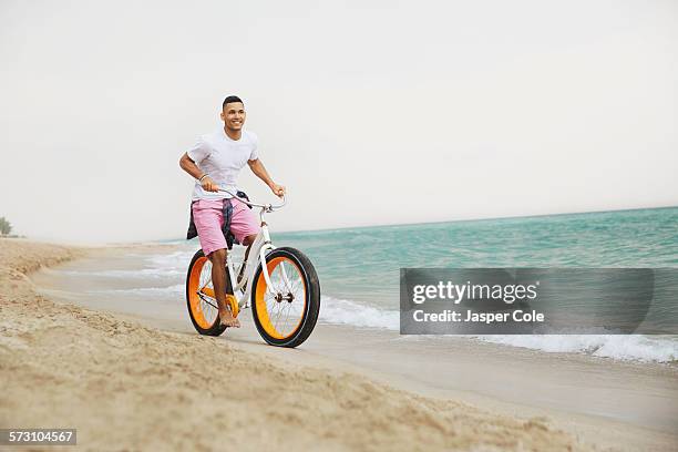 black man riding bicycle on beach - miami fahrrad stock-fotos und bilder