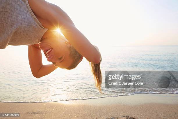 athlete tying hair in ponytail on beach - human hair strand stock pictures, royalty-free photos & images