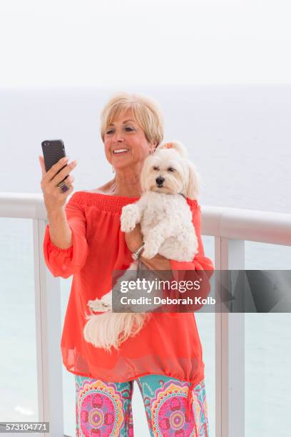 older caucasian woman taking selfie with dog on balcony - looking to the camera stockfoto's en -beelden