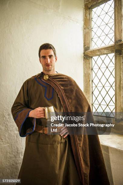 caucasian man in medieval costume standing at castle window - ceremonieel gewaad stockfoto's en -beelden