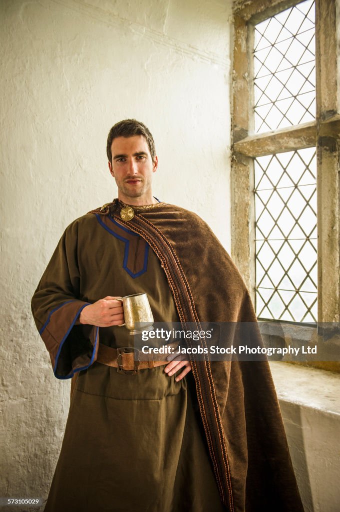 Caucasian man in medieval costume standing at castle window