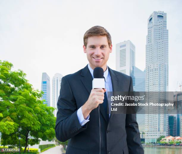 caucasian newscaster reporting in singapore cityscape - telecronista foto e immagini stock