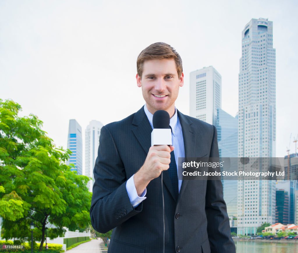 Caucasian newscaster reporting in Singapore cityscape