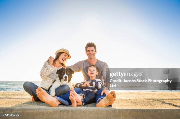 caucasian family sitting with dog on beach - family holidays australia stock-fotos und bilder