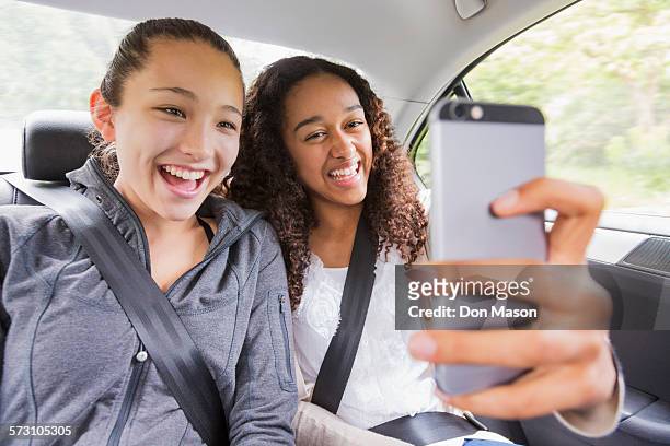 teenage girls using cell phone in car back seat - seat belt stock pictures, royalty-free photos & images