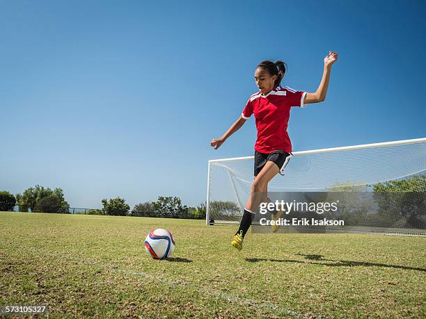 mixed race soccer player kicking ball on field - schoppen lichaamsbeweging stockfoto's en -beelden