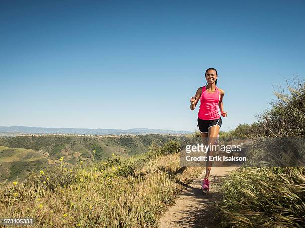 mixed race girl running on hillside path - girl mound stock-fotos und bilder