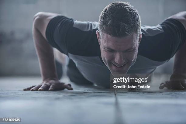 caucasian athlete doing push-ups on floor - entrenamiento de fuerza fotografías e imágenes de stock