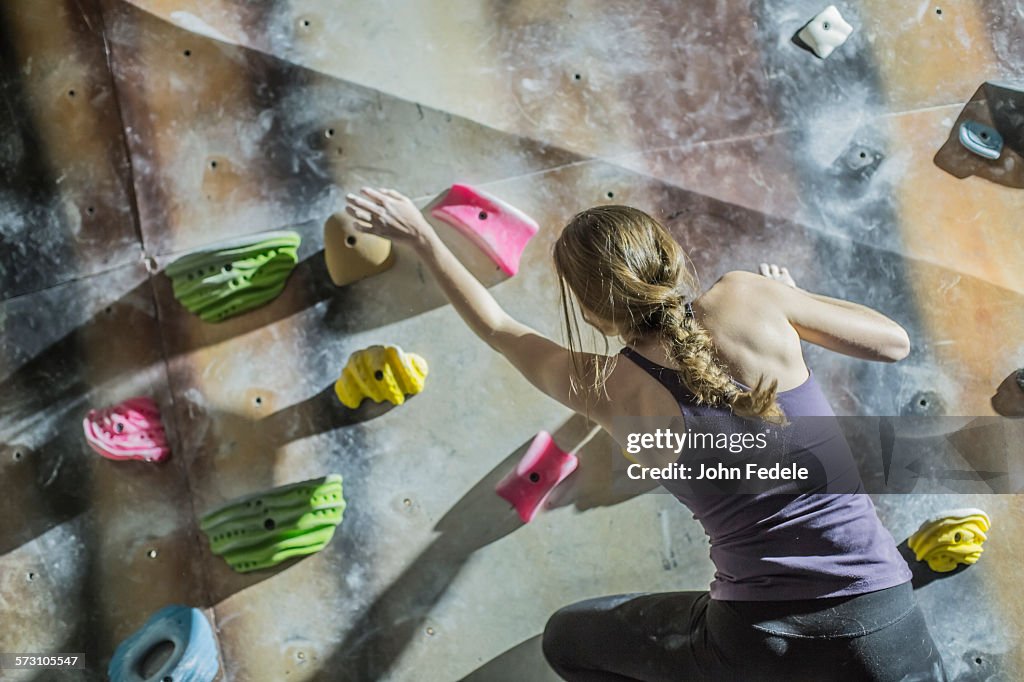 Athlete climbing rock wall in gym