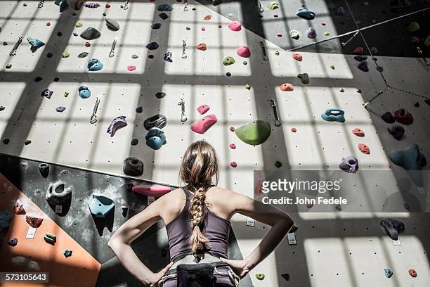 athlete examining rock wall in gym - förväntan bildbanksfoton och bilder