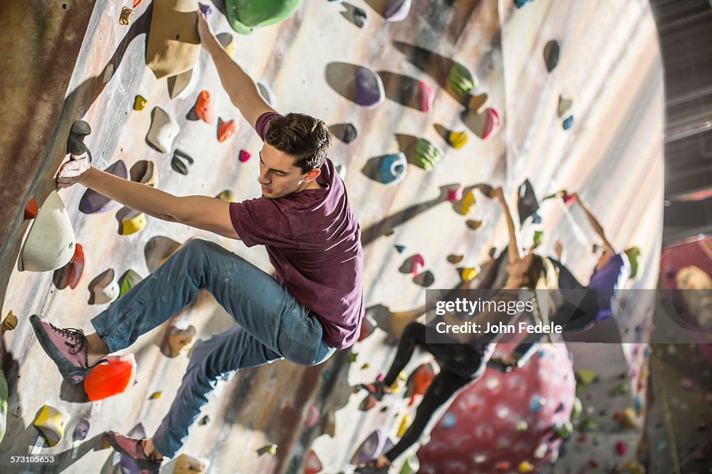 Athletes climbing rock wall in gym