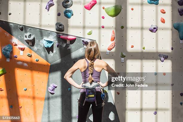 athlete examining rock wall in gym - bouldering stock pictures, royalty-free photos & images