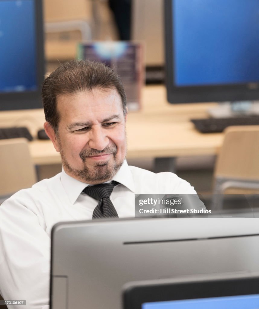 Hispanic businessman using computer in library