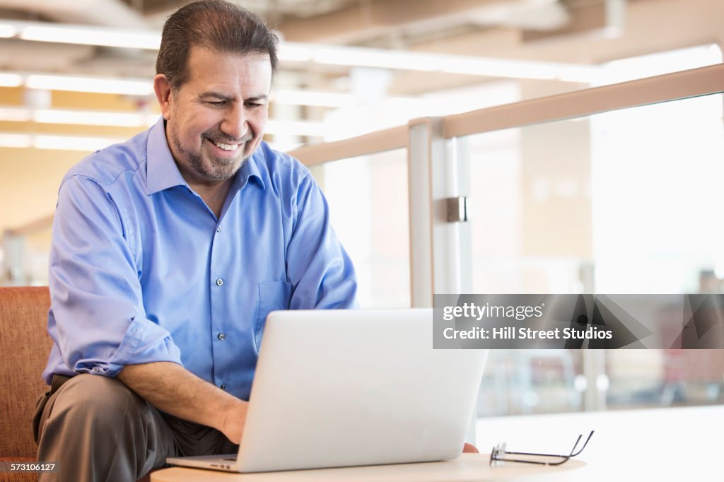 Hispanic businessman using laptop in office