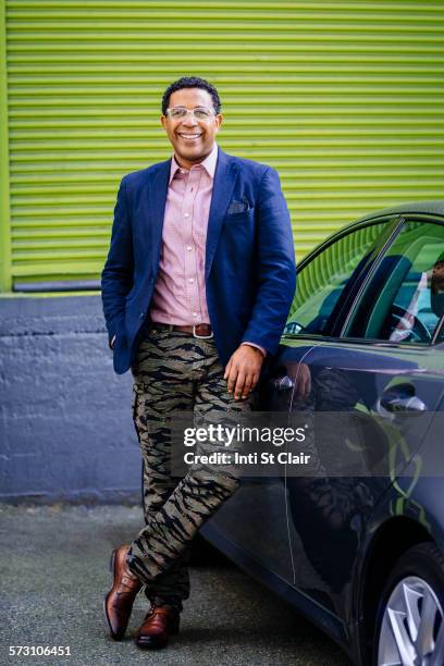 stylish mixed race businessman leaning on car - handsome native american men stock-fotos und bilder