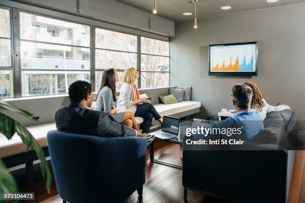 business people watching presentation in office lounge - loungeroom stock-fotos und bilder