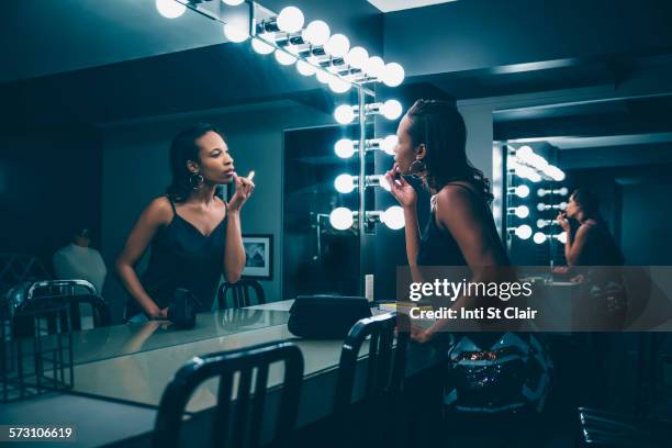 black woman applying makeup in vanity mirror - makeup mirror stock pictures, royalty-free photos & images