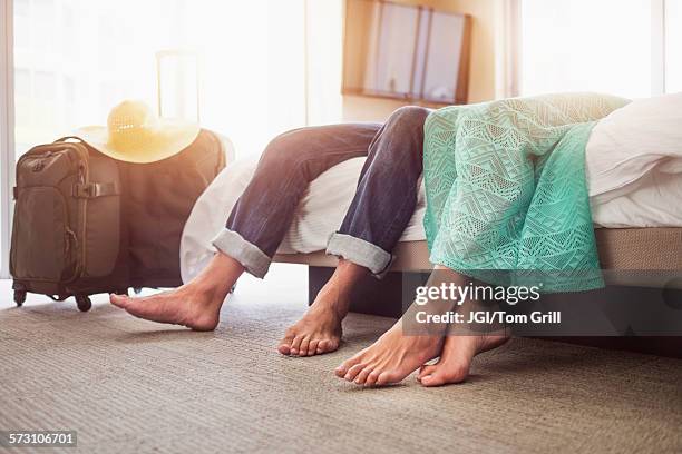 legs of couple laying on bed in hotel room - tired couple stock pictures, royalty-free photos & images
