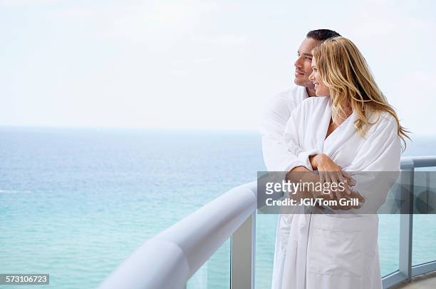 couple hugging on balcony over ocean - passenger craft stockfoto's en -beelden