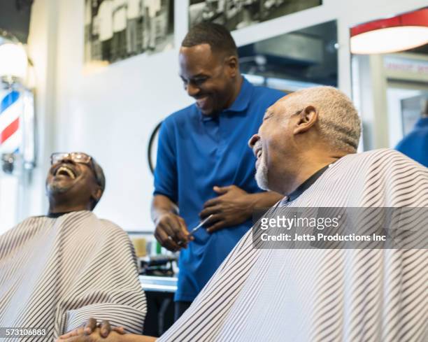 Black customers and barber laughing in retro barbershop